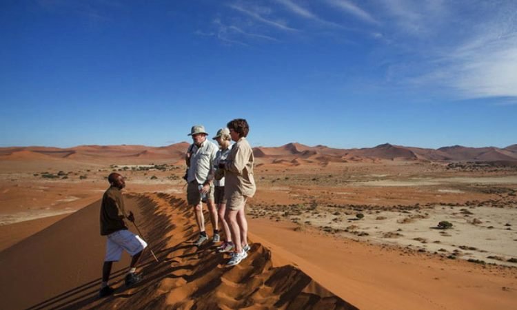 Traveler on the red dunes of Sossusvlei during a Namibia desert tour
